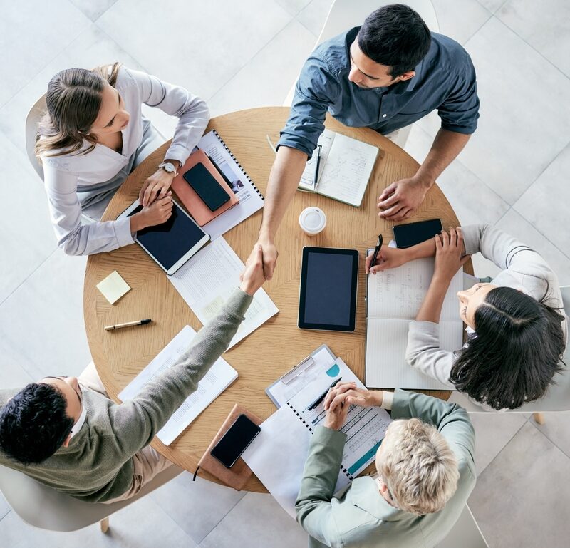 Meeting,,Handshake,And,Overhead,With,A,Business,Team,Sitting,Around